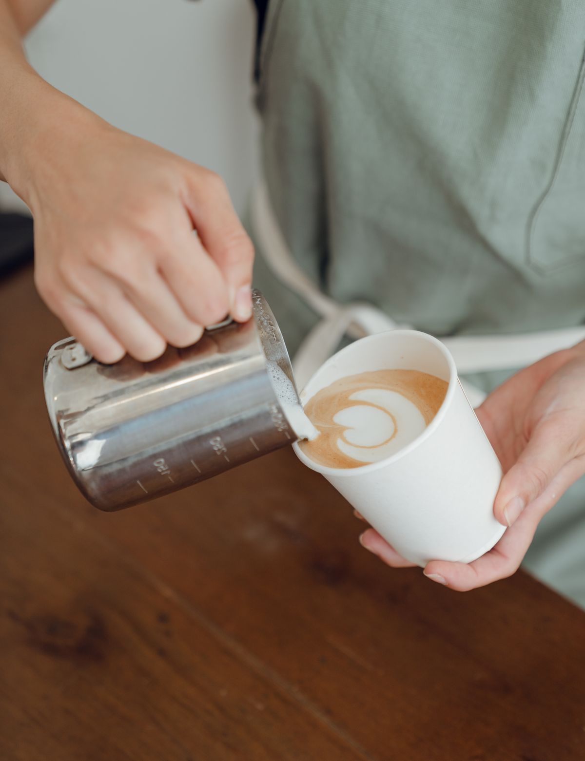 Barista gießt Milch für Latte Art in eine Kaffeetasse in einem Hamburger Café