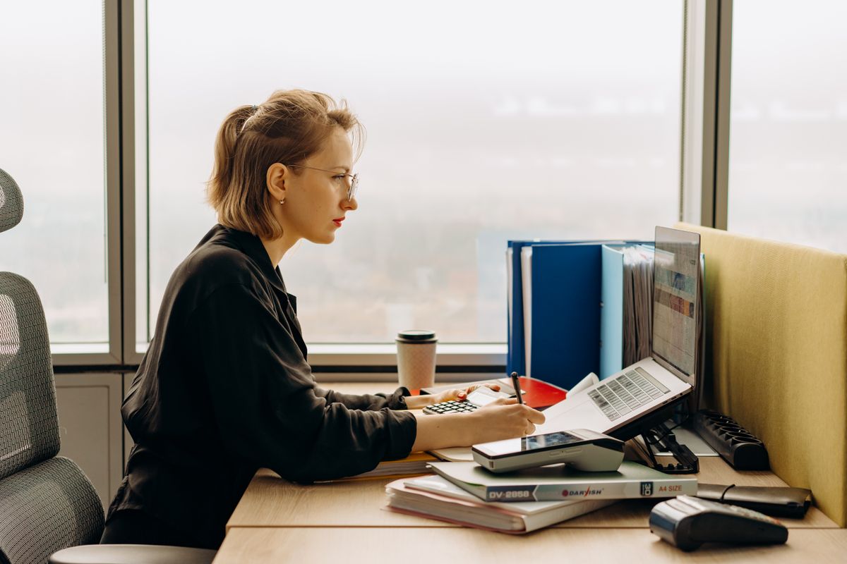 Wirtschaftsprüferin bei der Analyse von Finanzunterlagen am Laptop mit Blick über Hamburg