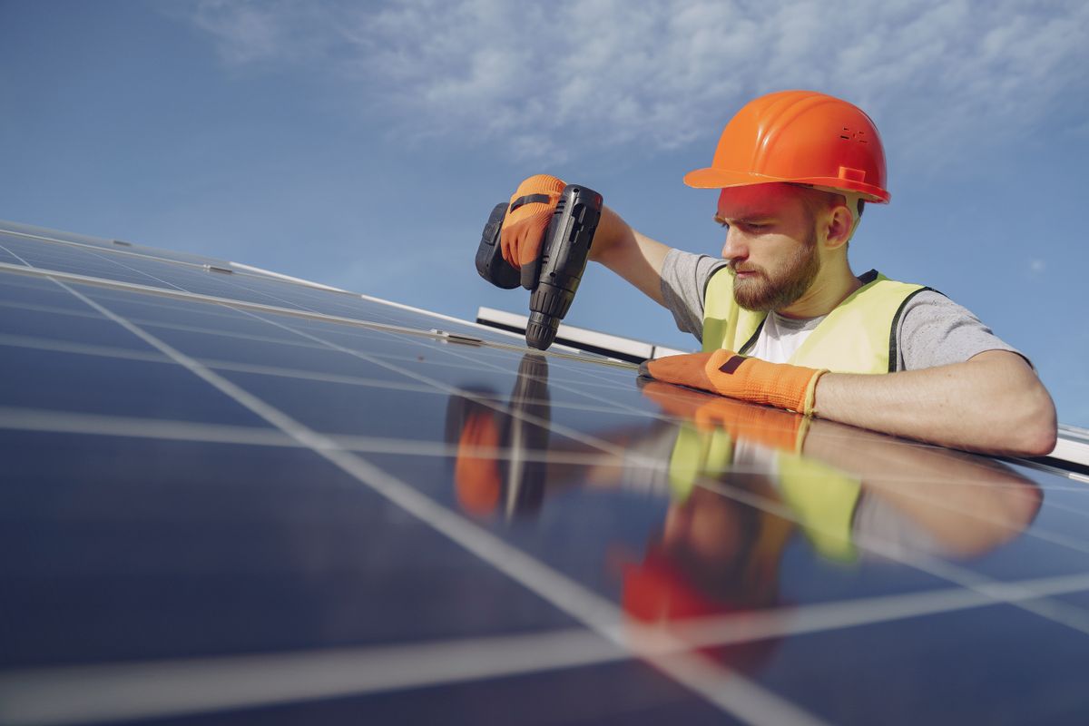 Elektriker installiert ein Photovoltaik-Modul auf einem Dach