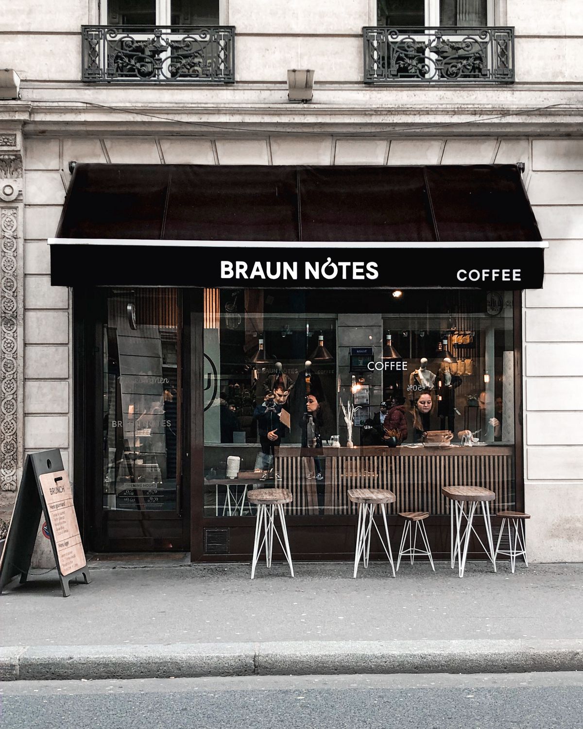 Moderne Ladenfront eines Franchise-Cafés mit Glasfassade und Straßenterrasse