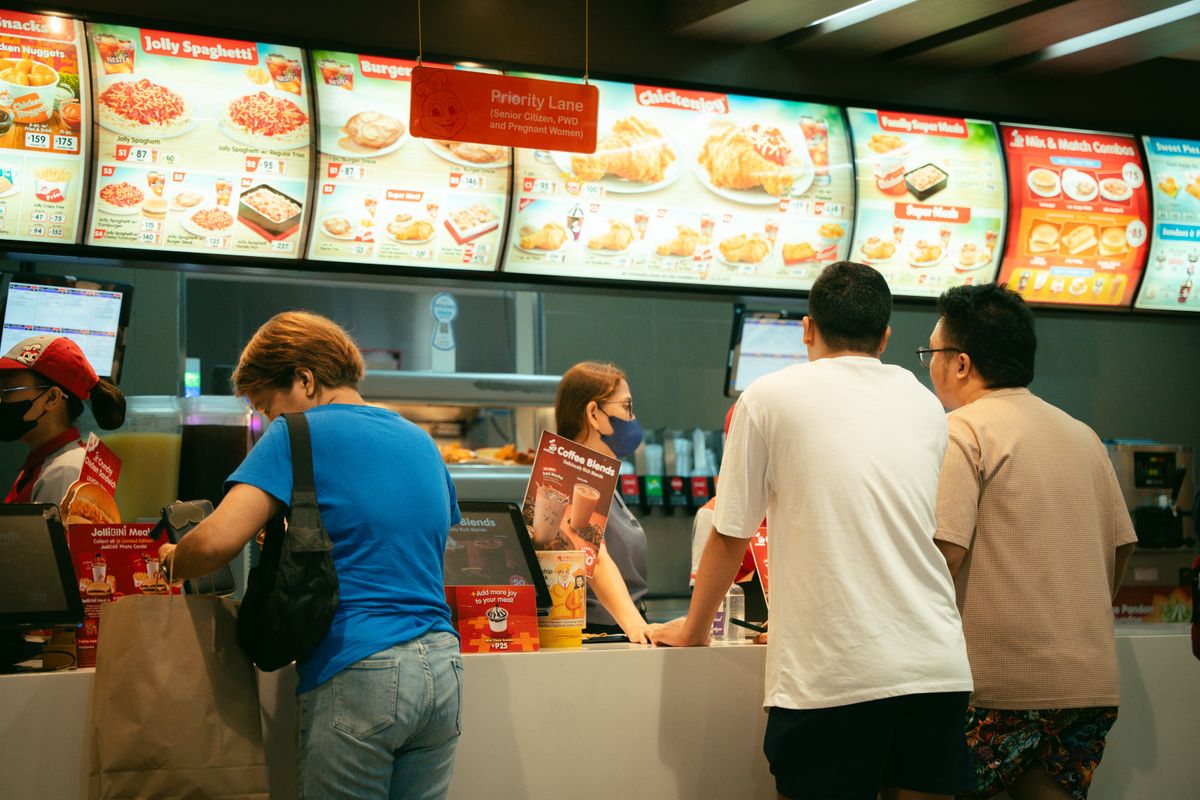 Kunden warten an der Theke einer Franchise-Filiale in der Systemgastronomie