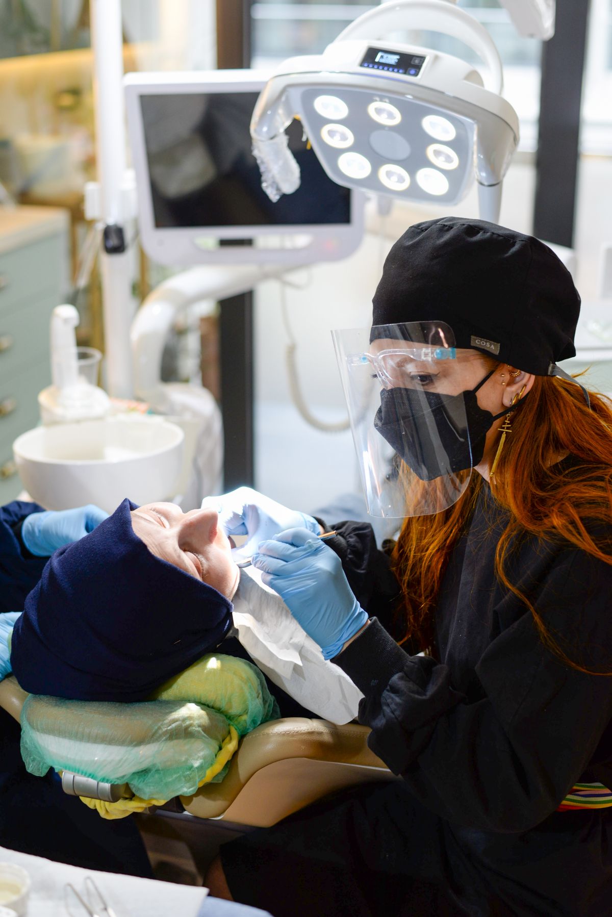 Kieferorthopädin behandelt eine Patientin unter professioneller Schutzausrüstung in der Praxis
