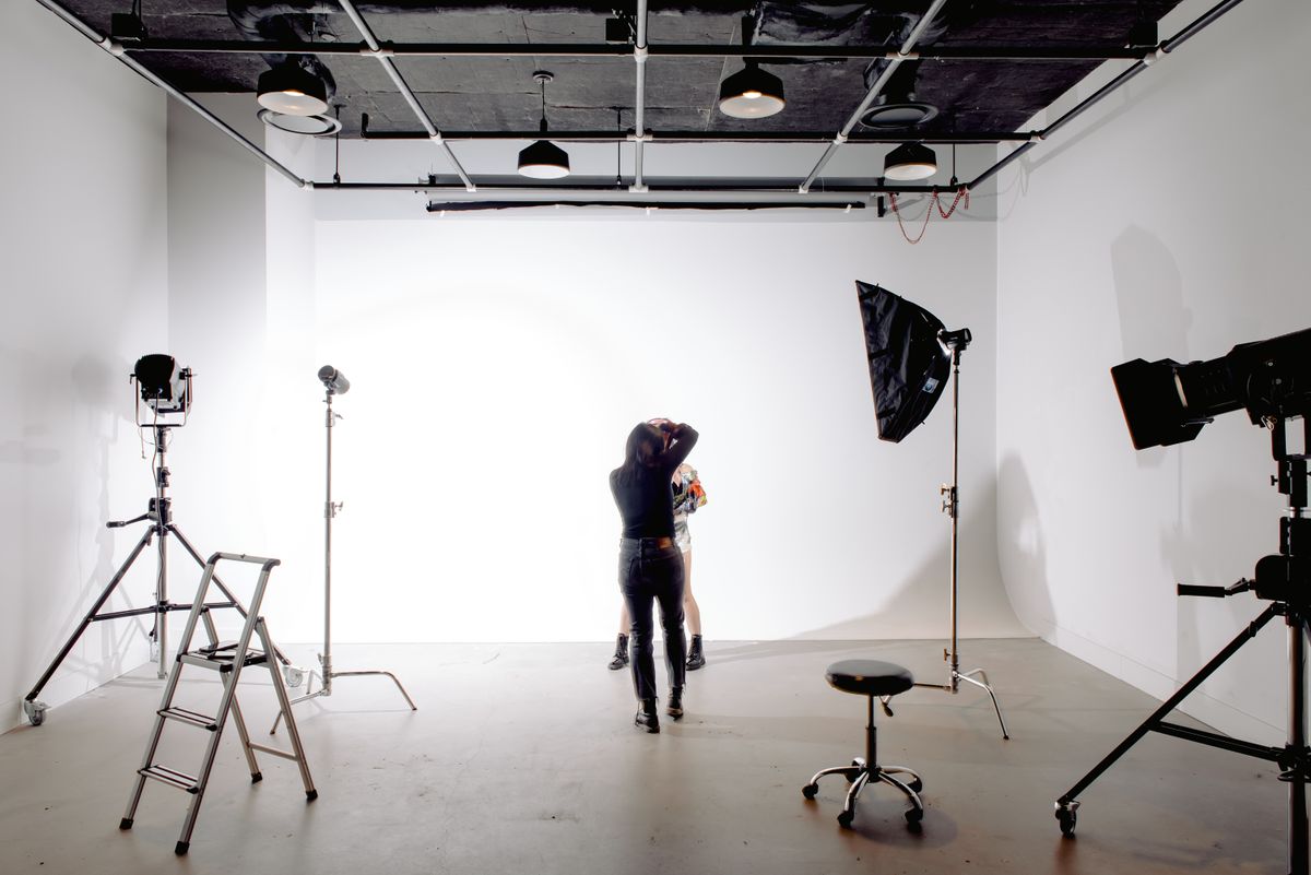 Professioneller Fotograf während eines Fotoshootings im Studio mit Beleuchtungsequipment