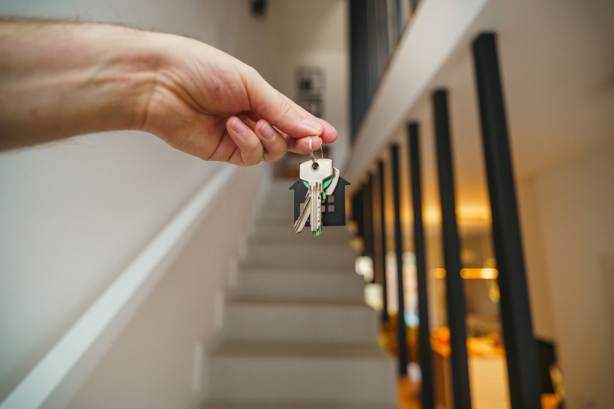 Hand hält Wohnungsschlüssel in einem modernen, frisch verwalteten Interieur