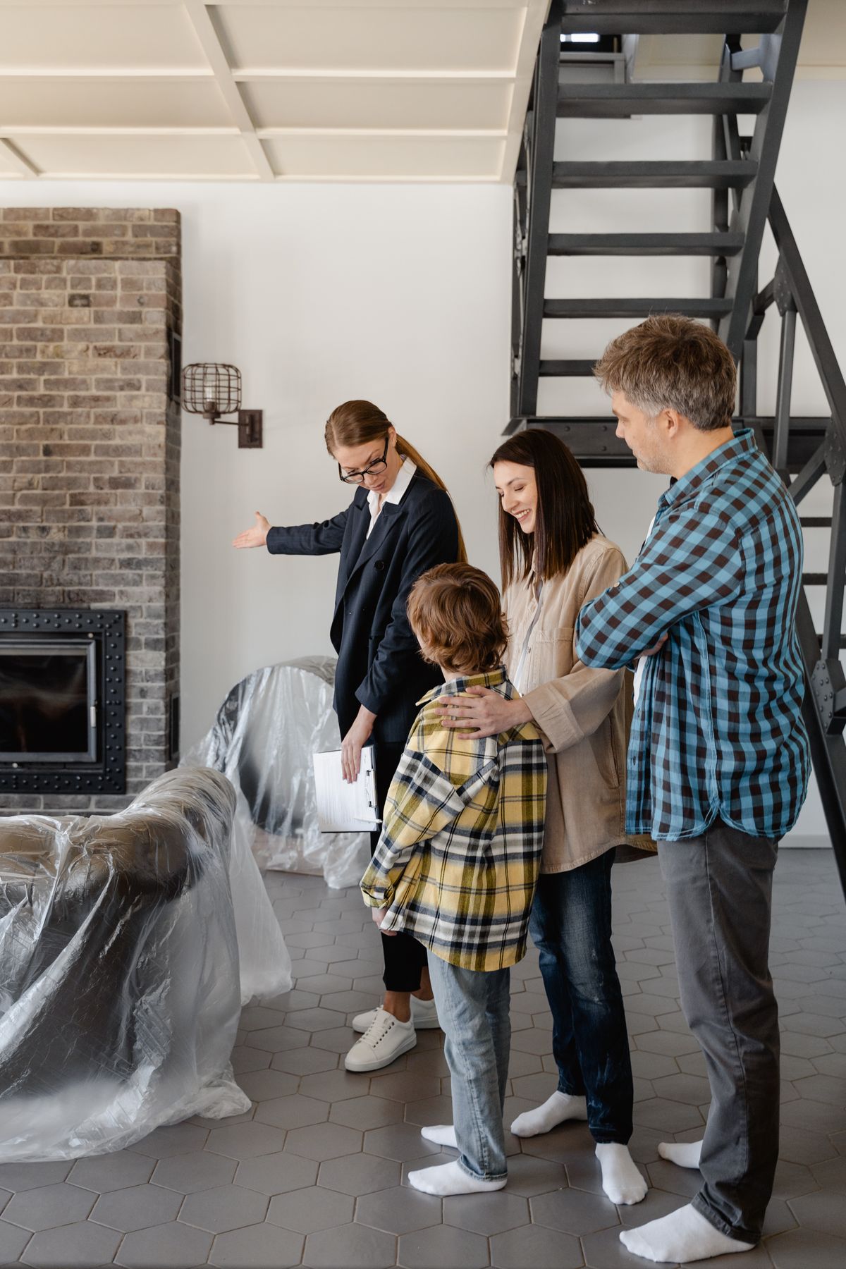 Immobilienmaklerin zeigt einem Ehepaar das Wohnzimmer einer Immobilie