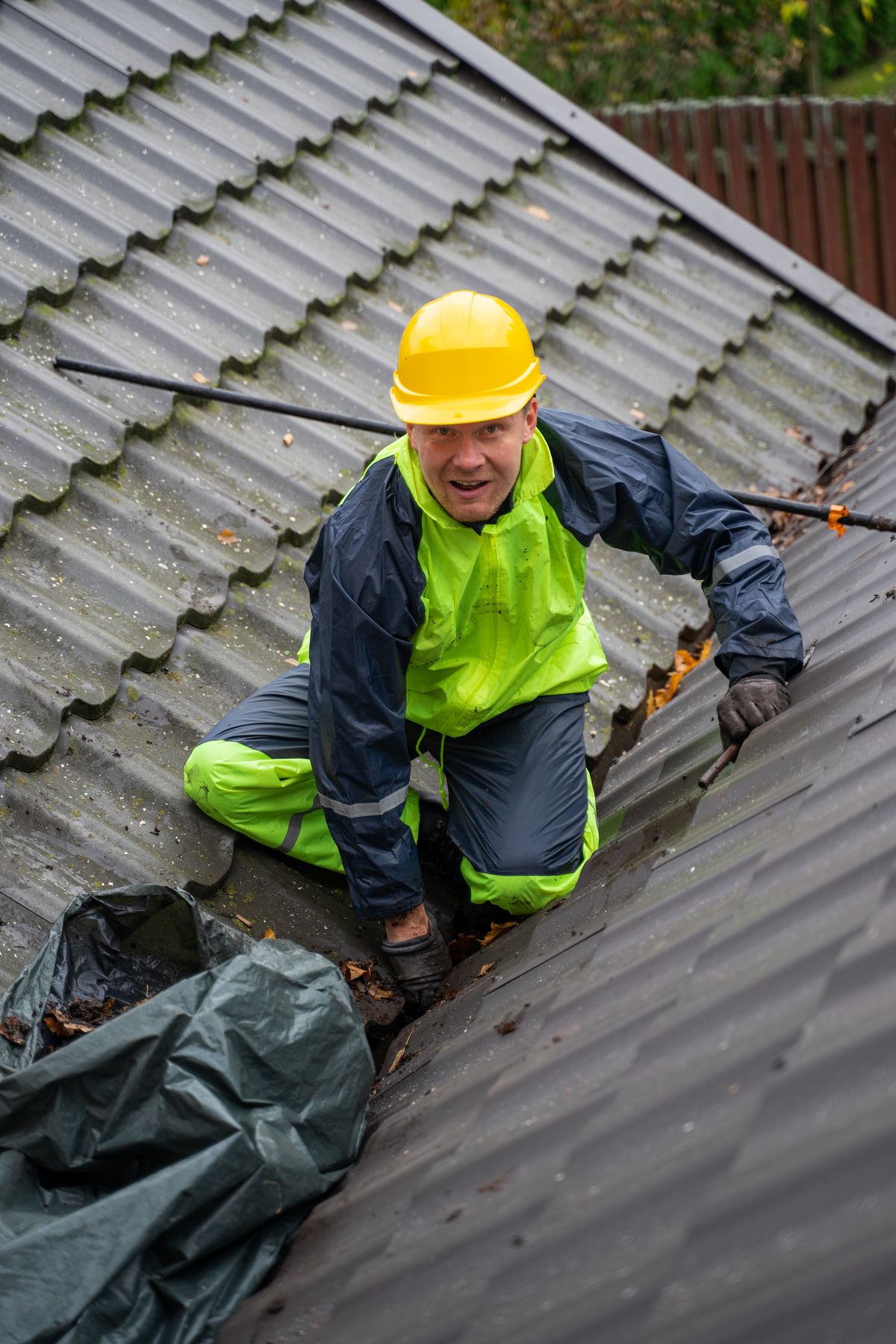 Dachdecker arbeitet auf einer Leiter am Dach eines Wohnhauses