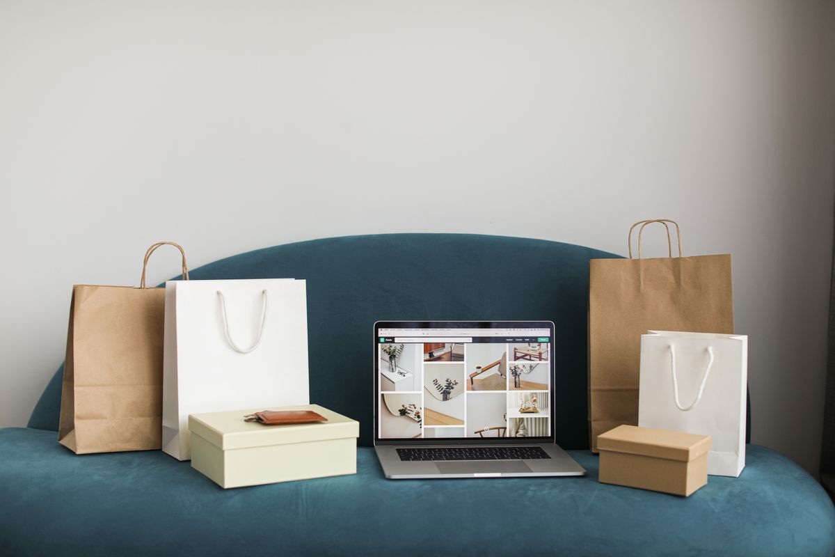 Laptop mit geöffnetem Onlineshop neben Versandkartons für Shopify-Bestellungen