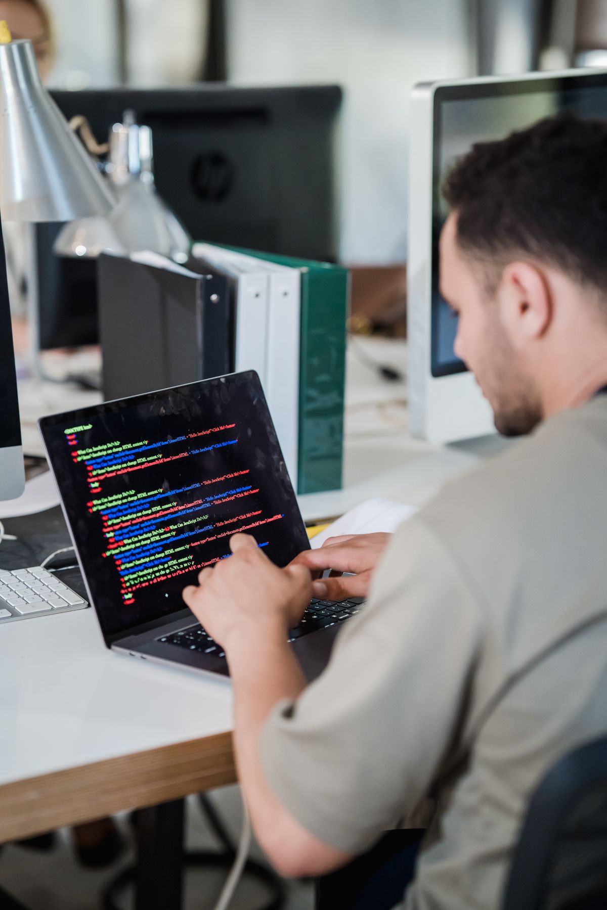 Softwareentwickler arbeitet konzentriert an Quellcode auf mehreren Bildschirmen