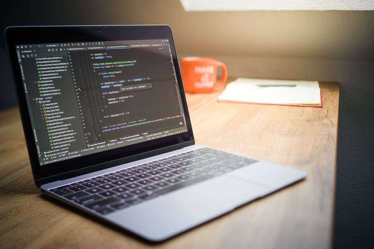 Moderner Arbeitsplatz mit Laptop und Quellcode auf dem Bildschirm in einem Softwareunternehmen